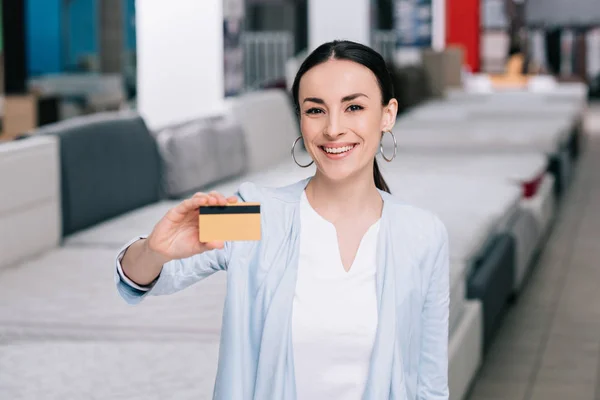 Улыбающаяся женщина показывает кредитку — стоковое фото