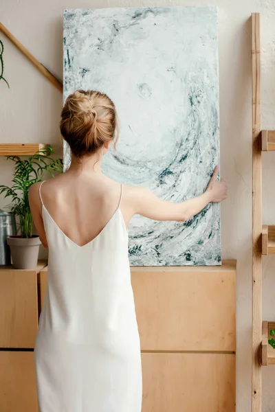 stock image back view of tender young female artist holding picture in studio 