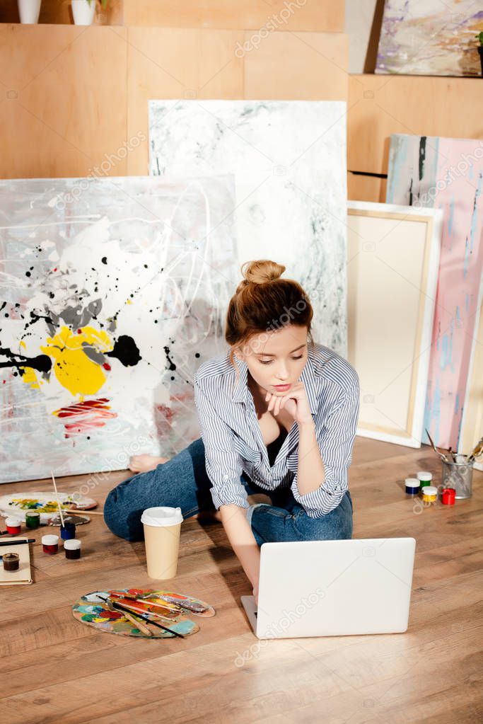 beautiful young artist using laptop in art studio
