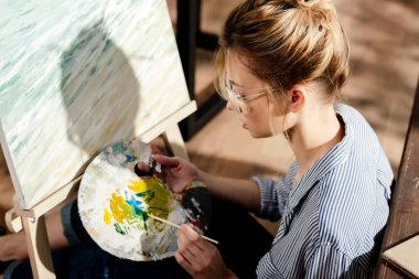 şık kadın sanatçı paletini kullanarak gözlük içinde yan görünüm 