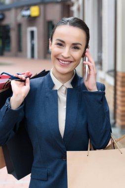 Smartphone ile konuşmak ve alışveriş torbaları tutan çekici işkadını