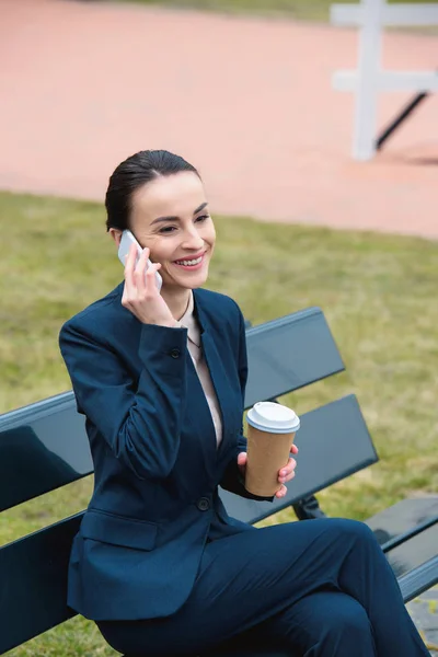 Smiling Businesswoman Talking Smartphone Holding Coffee Paper Cup Bench — Free Stock Photo