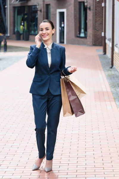 Lachende Aantrekkelijke Zakenvrouw Holding Boodschappentassen Praten Door Smartphone — Gratis stockfoto