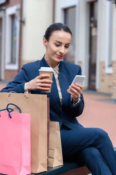 Çekici Işkadını Alışveriş Sonra Bankta Smartphone Kullanarak — Ücretsiz Stok Fotoğraf