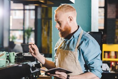 genç erkek barista ayakta kafede ders kitabı ile 