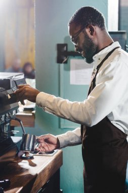 mutlu genç Afro-Amerikan barista kahve makinesi kahve gözlük içinde yan görünüm 