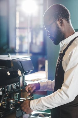Genç Afro-Amerikan barista kahve makinesi kahve hazırlama gözlük içinde yan görünüm