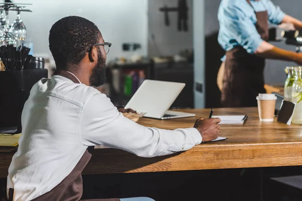 Joven Afroamericano Barista Masculino Escritura Libro Texto Colega Utilizando Máquina — Foto de Stock