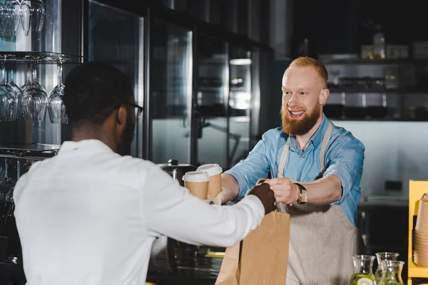 Smiling Bearded Young Barista Giving Paper Bag Disposable Coffee Cups — Stock Photo, Image