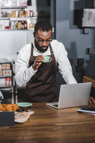 Joven Africano Americano Barista Celebración Taza Café Uso Computadora Portátil — Foto de Stock