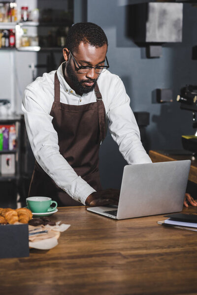 young african american barista using laptop while working in cafe