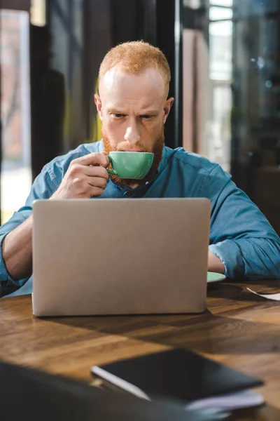 Bello Giovane Che Beve Caffè Utilizza Computer Portatile Nel Caffè — Foto Stock