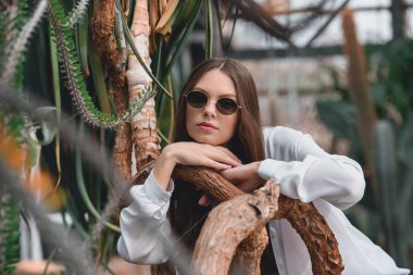 tropikal bahçede poz trendy güneş gözlüğü güzel kız