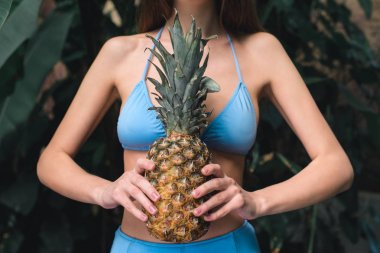 Kısmi ananas tutan mavi bikinili kız görünümünü  