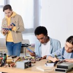 Multiculturele tieners solderen circuit van de computer en moederbord thuis