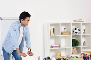 sandalyeye yaslanmış ve masada teknik ekipman ile evde seyir Afrikalı-Amerikalı genç