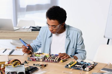 Afrikalı-Amerikalı genç bilgisayar devre ile evde havya lehimleme
