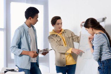 Beyaz genç çocuk bir şey çok kültürlü gençler evde flipchart üzerinde sunulması