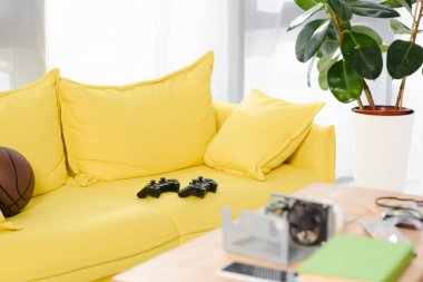Sarı kanepe evde gamepads ve basketbol topu