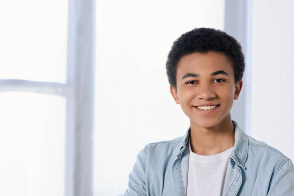 smiling african american teenager looking at camera at home