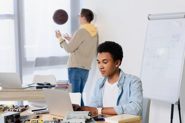 Africano Americano Adolescente Chico Usando Laptop Amigo Jugando Con Baloncesto — Foto de stock gratis