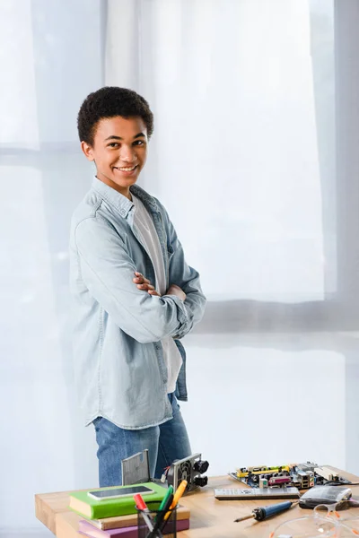 Sonriente Afroamericano Adolescente Pie Con Los Brazos Cruzados Cerca Mesa — Foto de Stock