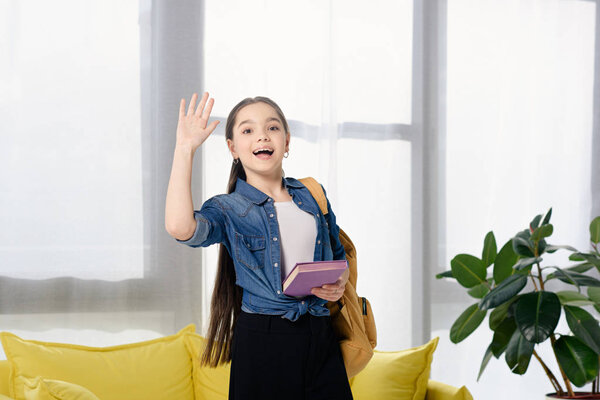 adorable preteen child waving hand at home