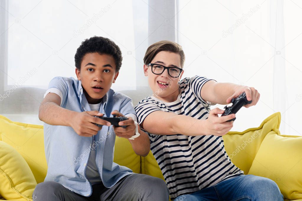 multicultural teen boys playing video game at home