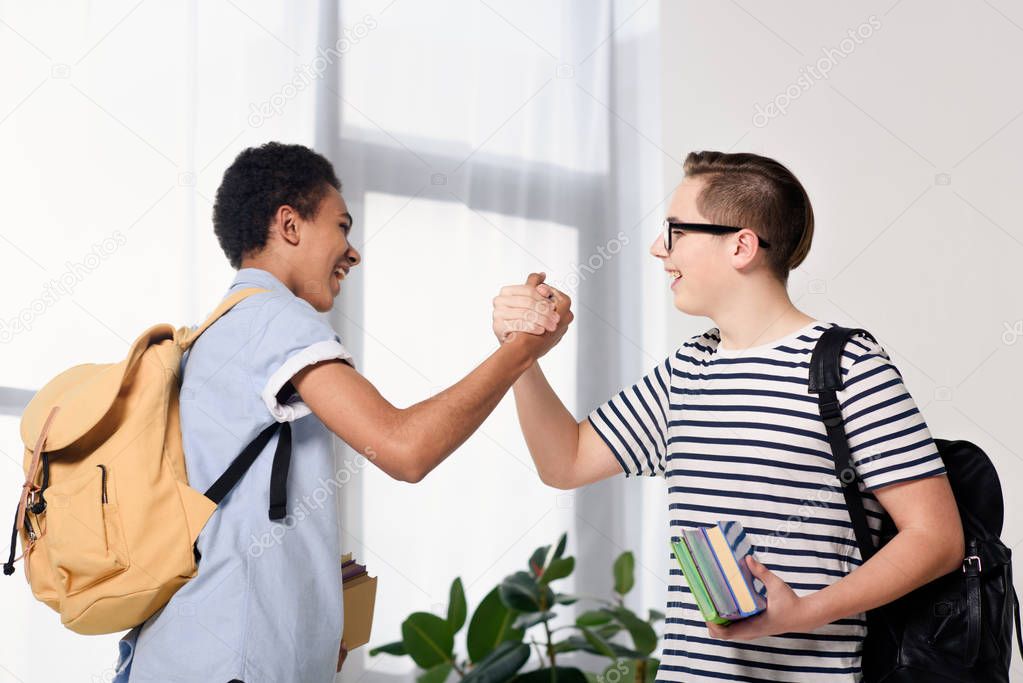 side view of multicultural teen boys greeting at home