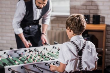 father and son in vintage clothing playing table football clipart