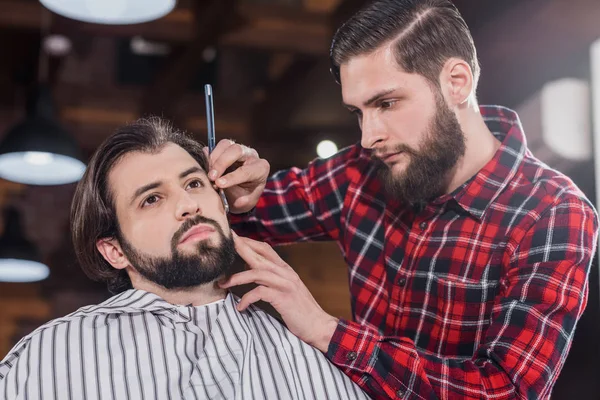 Selbstbewusster Junger Friseur Karierten Hemd Rasiert Mann Mit Haarschneidemaschine — Stockfoto