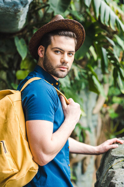 attractive young man in stylish clothes in rainforest