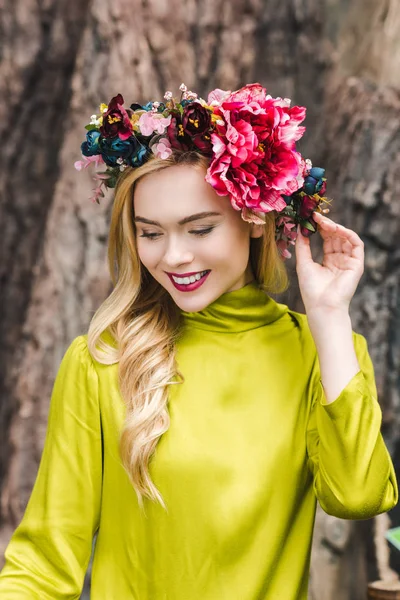 Uśmiechnięta Młoda Kobieta Wieniec Kwiatowy Patrząc Dół — Darmowe zdjęcie stockowe