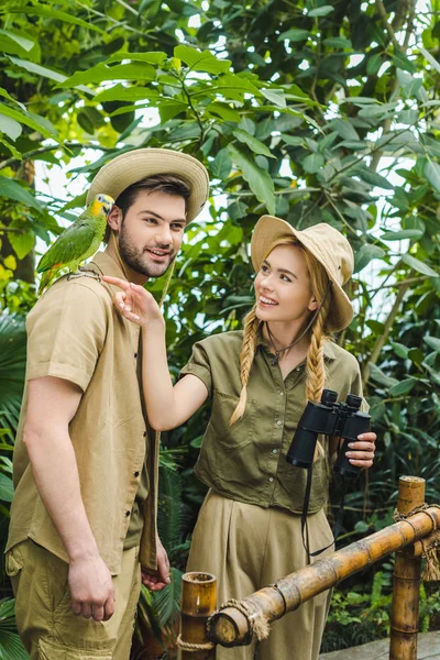 attractive young couple in safari suits with binoculars hiking together in rainforest