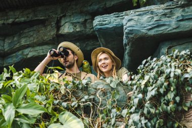 Alt görünümü içinde safari heyecanlı genç çiftin ormanda cliff üzerinde dürbün ile uygun