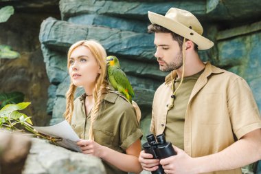 Safari'de güzel genç çift ormanda gezinmek çalışıyor papağan ile uygun