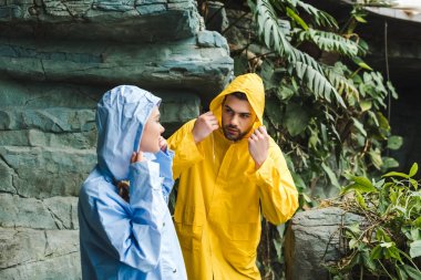 attractive young couple in raincoats in jungle clipart