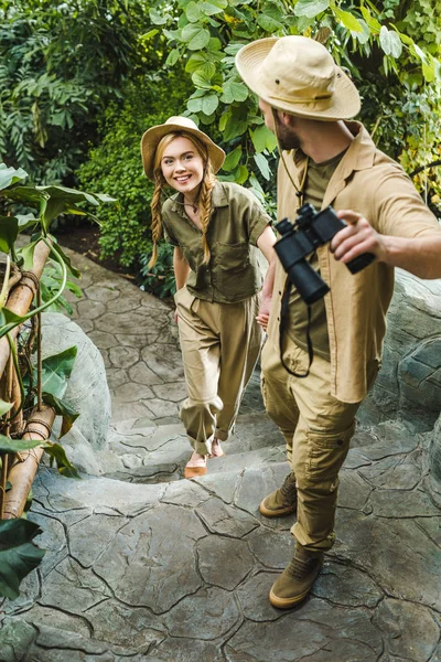 beautiful young couple in safari suits hiking together in rainforest