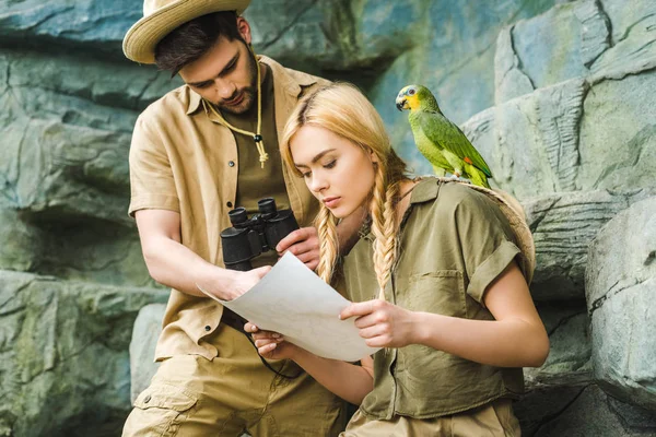 beautiful young couple in safari suits with parrot hiking in jungle