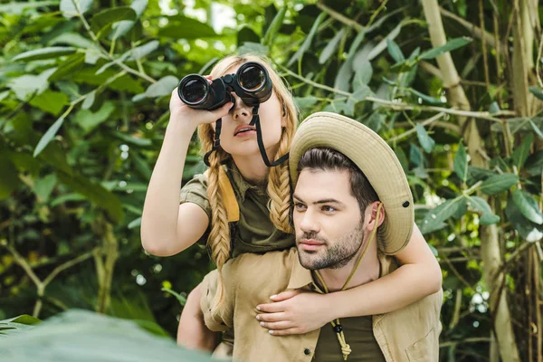 美丽的年轻夫妇在野生动物园穿着双筒望远镜在丛林中徒步旅行 — 图库照片