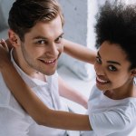 African american girl embracing boyfriend by light wall