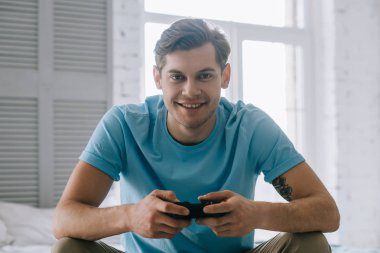 Adam yatakta otururken video oyun oynarken joystick ile