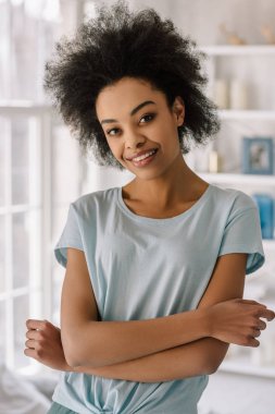 Evde poz gülümseyen genç Afro-Amerikan kadın