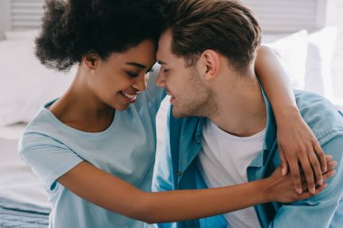 Young woman embracing boyfriend while sitting on bed clipart