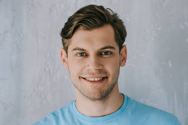 Close-up shot of young man smiling by gray wall