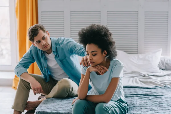 男人和他的非洲裔美国女友聊天坐在床上 — 图库照片