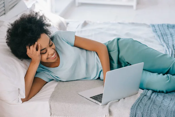 Yatakta Yatarken Dizüstü Bilgisayar Ekranına Bakarak Afrikalı Amerikalı Kadın — Stok fotoğraf