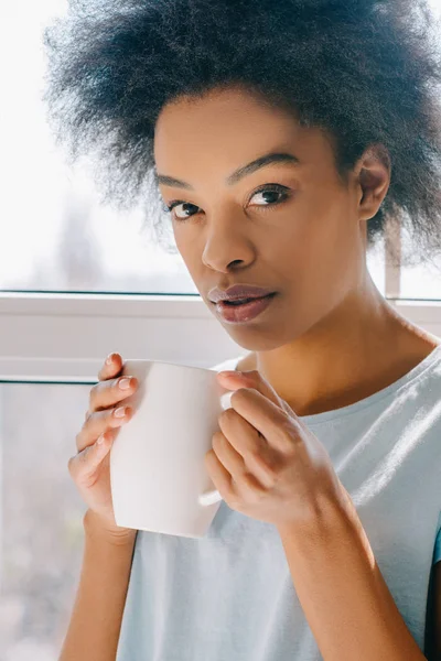 ラウンジでアフリカ系アメリカ人の女の子がカップからコーヒーを飲むを着用します — ストック写真
