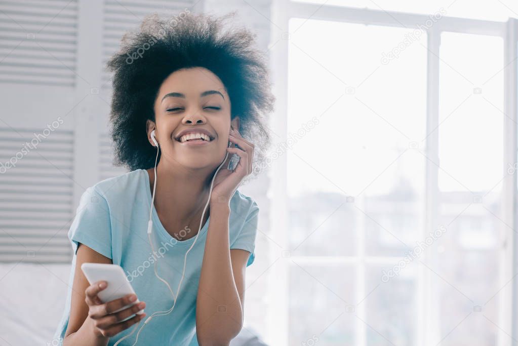 Smiling african american girl enjoying music in earphones
