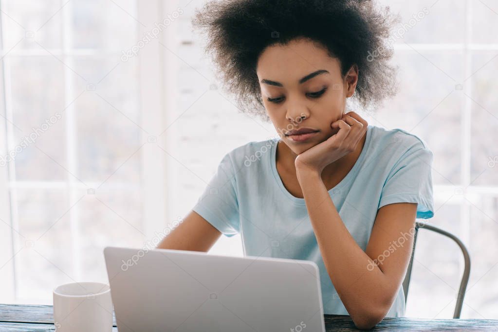 Thoughtful african american woman working on laptop at home